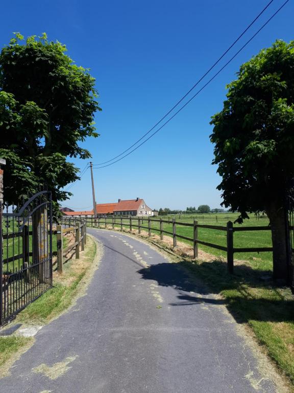 uma estrada com cerca e árvores ao lado em de blinker em Knokke-Heist