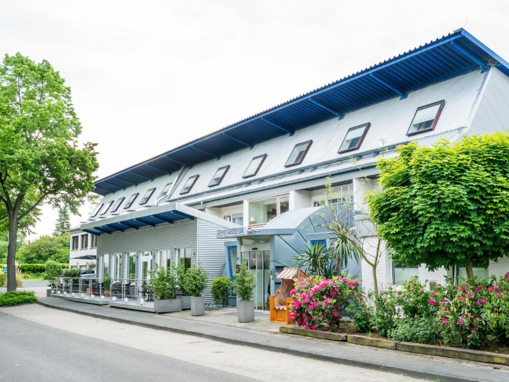 a white building with flowers on the side of a street at Hotel Hangelar in Sankt Augustin