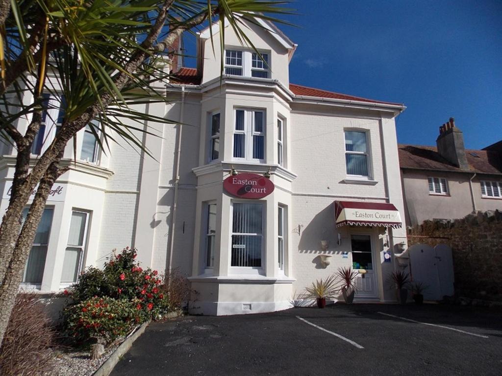 a white house with a red sign in front of it at Easton Court Guest House in Paignton