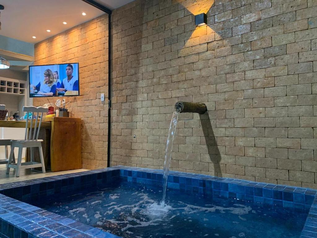 a swimming pool with a water fountain in a room at Vila dos Milagres Casa de Charme in São Miguel dos Milagres
