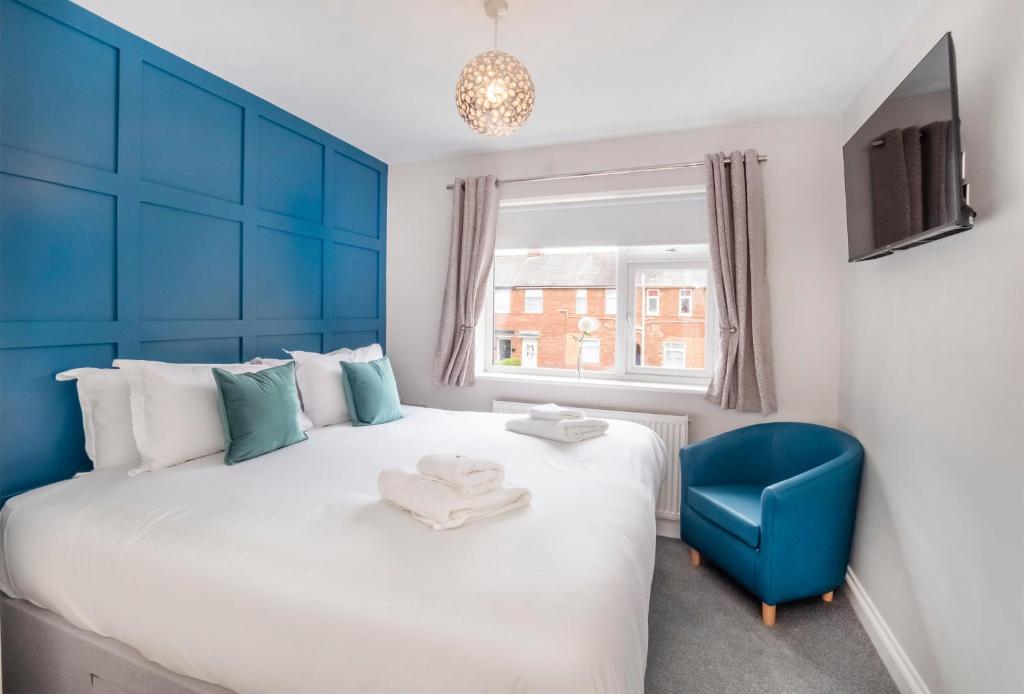 a bedroom with a blue headboard and a blue chair at Hope Street House in York