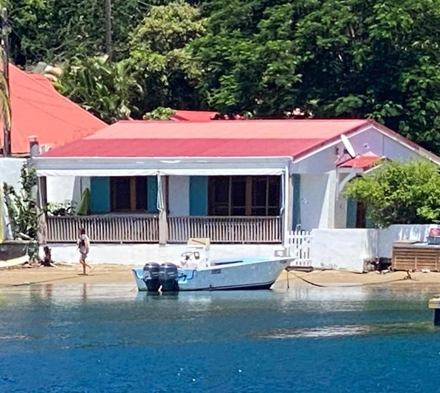 una barca di fronte a una casa sull'acqua di Villa GRENADINE Vue panoramique, les pieds dans l'eau a Terre-de-Haut
