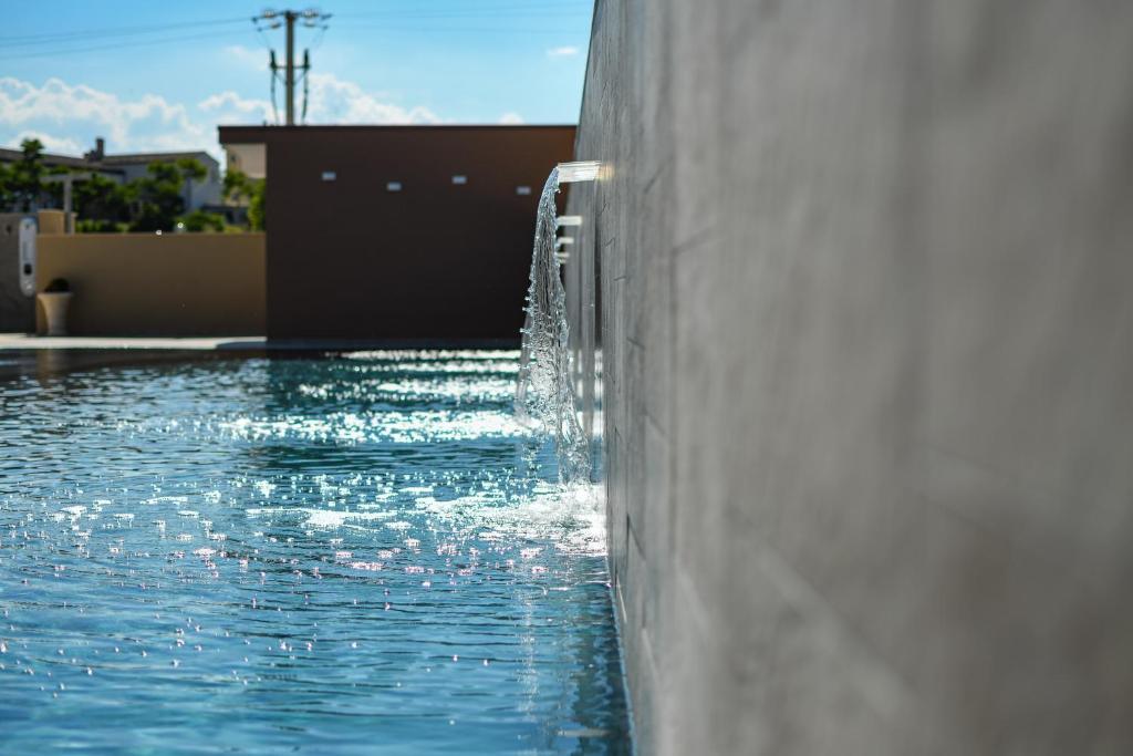 a swimming pool with a water fountain on the side of a building at Hotel Baffo Rosso in Alba Adriatica