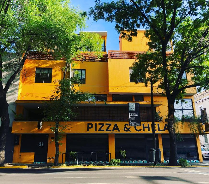 un edificio giallo con un ristorante di pizza e relax di Hostal Hidalgo a Guadalajara