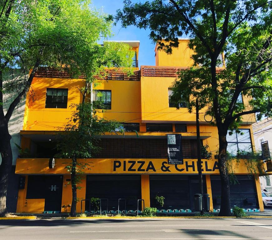 a yellow building with a pizza and chill restaurant at Hostal Hidalgo in Guadalajara
