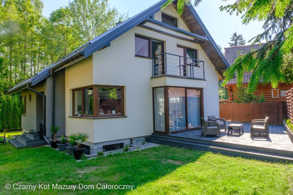 ein Haus mit einer Terrasse und einem Hof in der Unterkunft Czarny Kot Mazury Dom Całoroczny in Małkinie