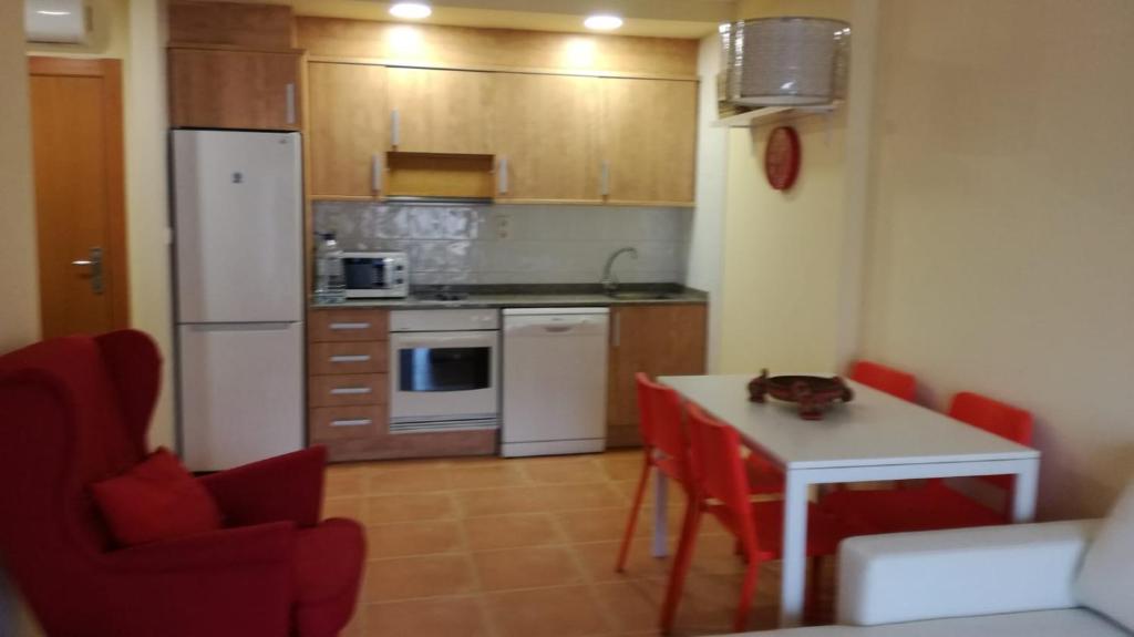 uma cozinha com um frigorífico branco e uma mesa com cadeiras vermelhas em Nova Almenara. Ideal para familias em Barrio-Mar