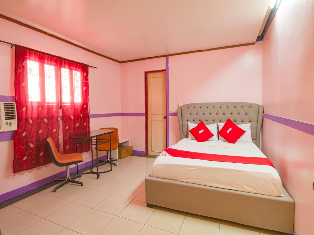 a bedroom with a bed with red pillows and a table at OYO 790 Mango Inn in Manila