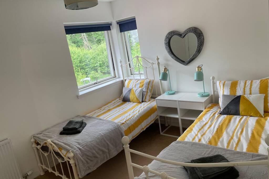 a bedroom with two beds and a heart mirror on the wall at Woodside retreat holiday home in Aviemore in Aviemore