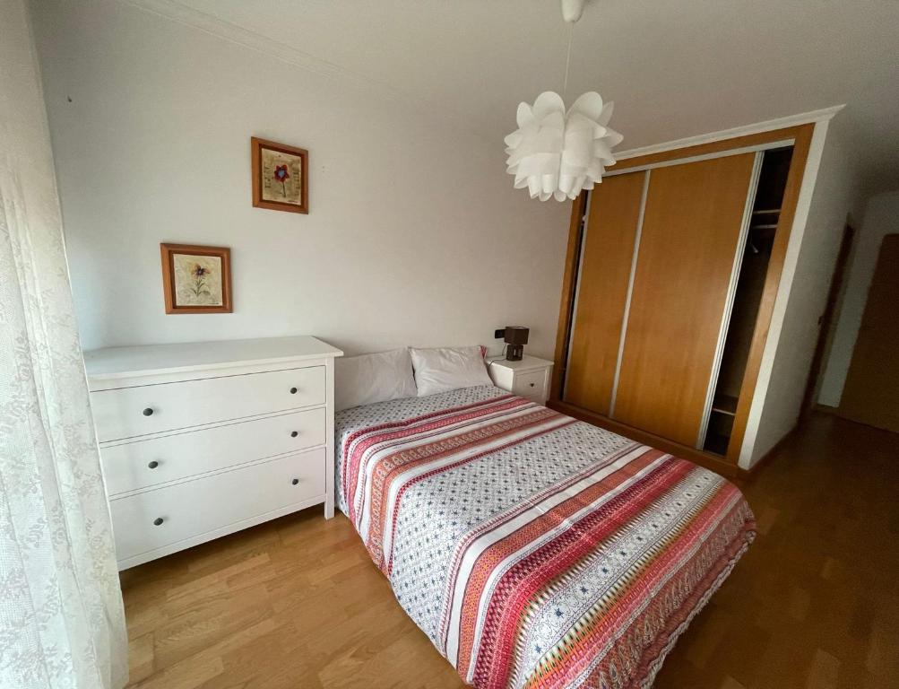 um quarto com uma cama, uma cómoda e um lustre em Apartamento en la playa em Ribeira