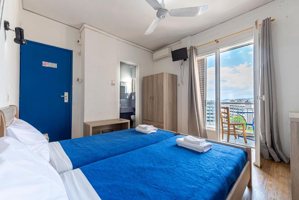 een slaapkamer met een blauw bed en een balkon bij Sparta Team Hotel in Athene