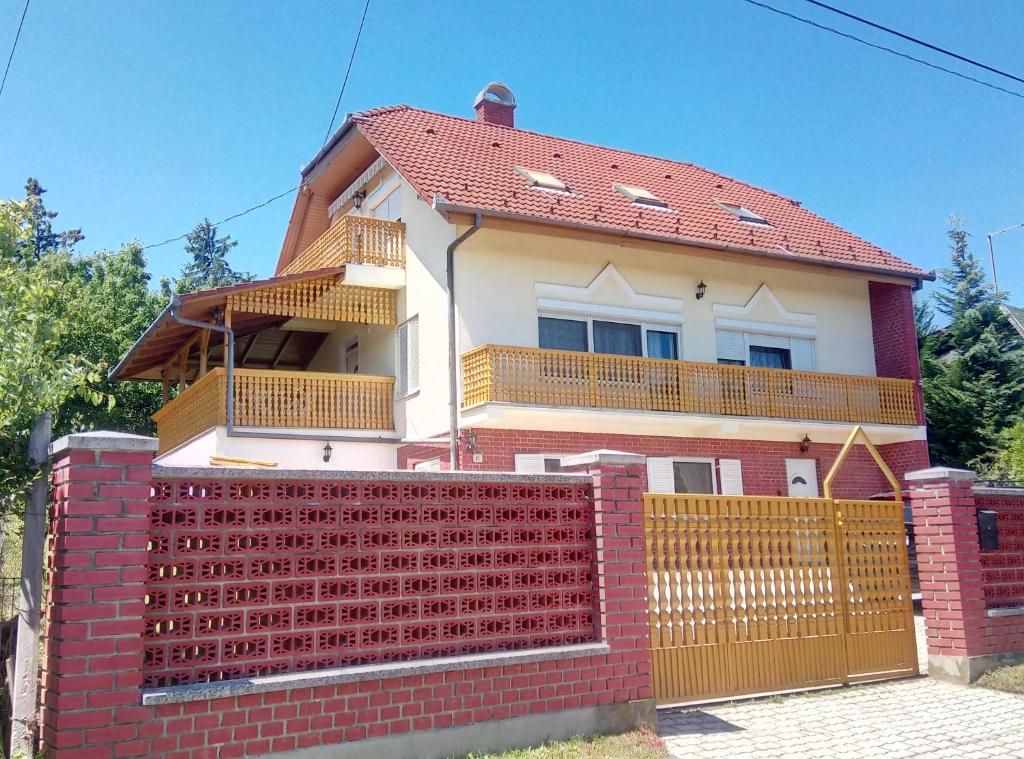 een huis met een rode bakstenen hek ervoor bij Piroska Apartment in Zalakaros