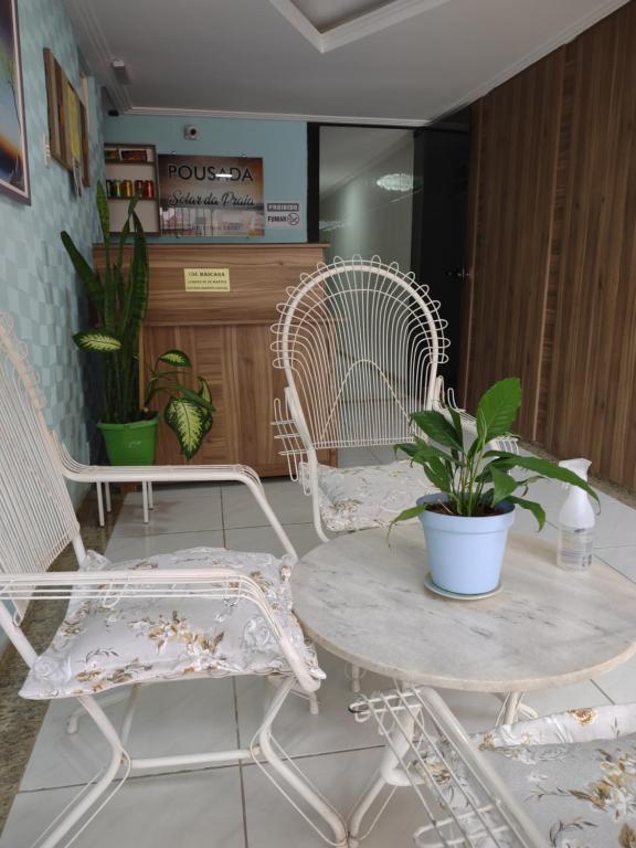 瓜拉帕里的住宿－Pousada Solar da Praia，一间房间,配有两把椅子和一张桌子,种植了盆栽植物
