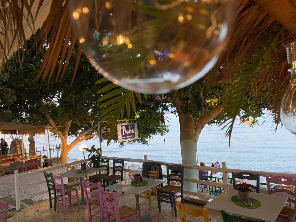 a wine glass hanging above tables and chairs on the beach at Bob's Apartments in Tolo