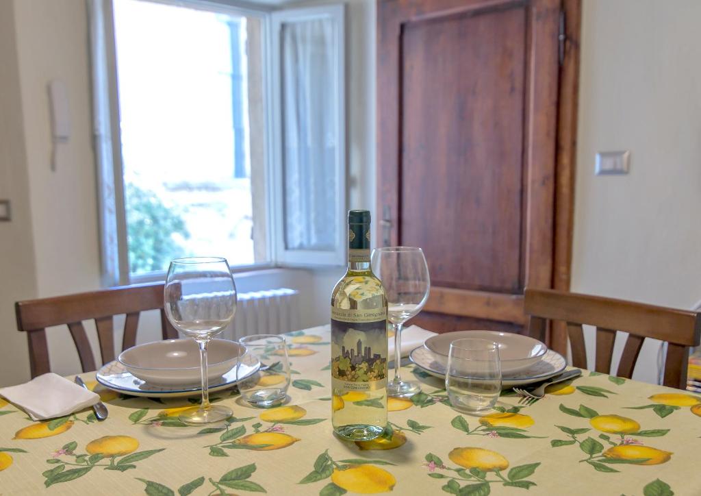 una bottiglia di vino seduta su un tavolo con bicchieri di Appartamento Benozzo a San Gimignano