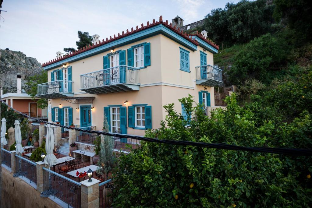 duży dom z niebieskimi oknami i balkonem w obiekcie Acronafplia Pension A w Nauplionie