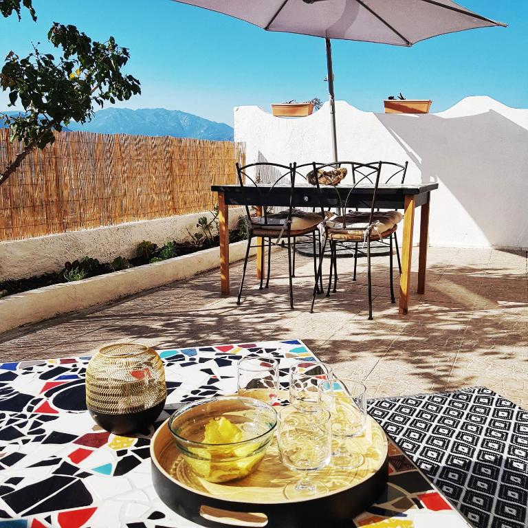 - une table, des chaises et un parasol sur la terrasse dans l'établissement Appartement T2bis Sartène 60m2 avec jolie terrasse de 25m2 et vue panoramique mer et montagne sur le Golfe du Valinco - Quartier calme à 10mn à pied du centre ville - Idéal pour 4 personnes et possibilité de 6 couchages - Place de parking réservée, à Sartène
