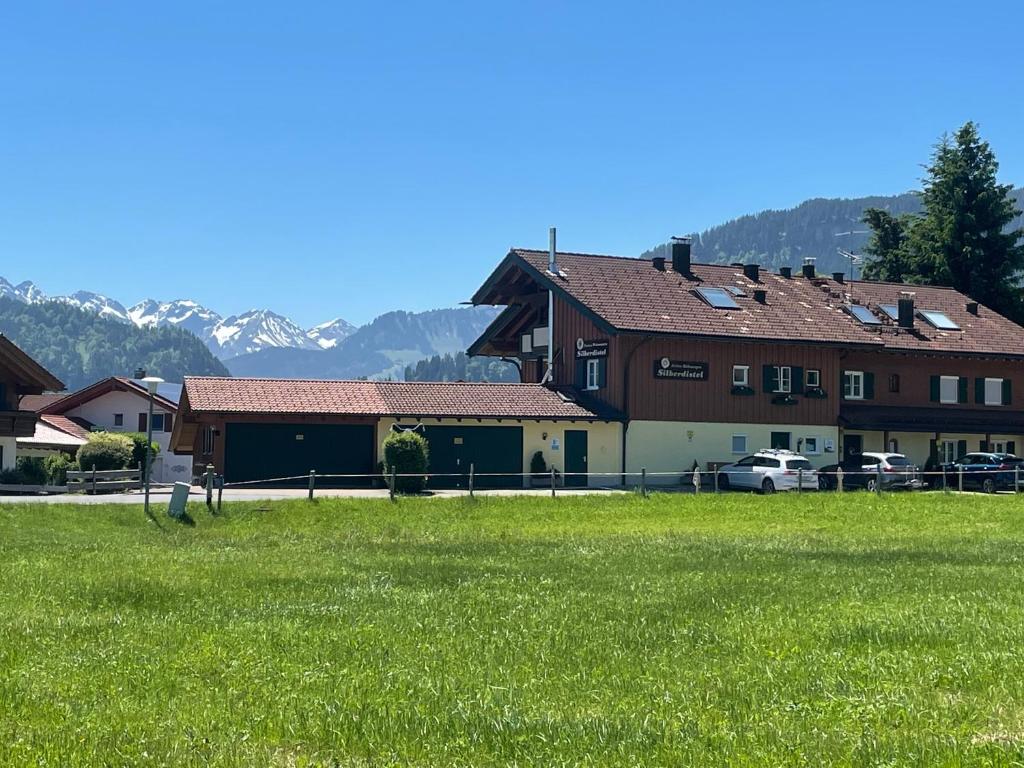 a house with a green field in front of a building at Ferienhotel Silberdistel garni in Bolsterlang