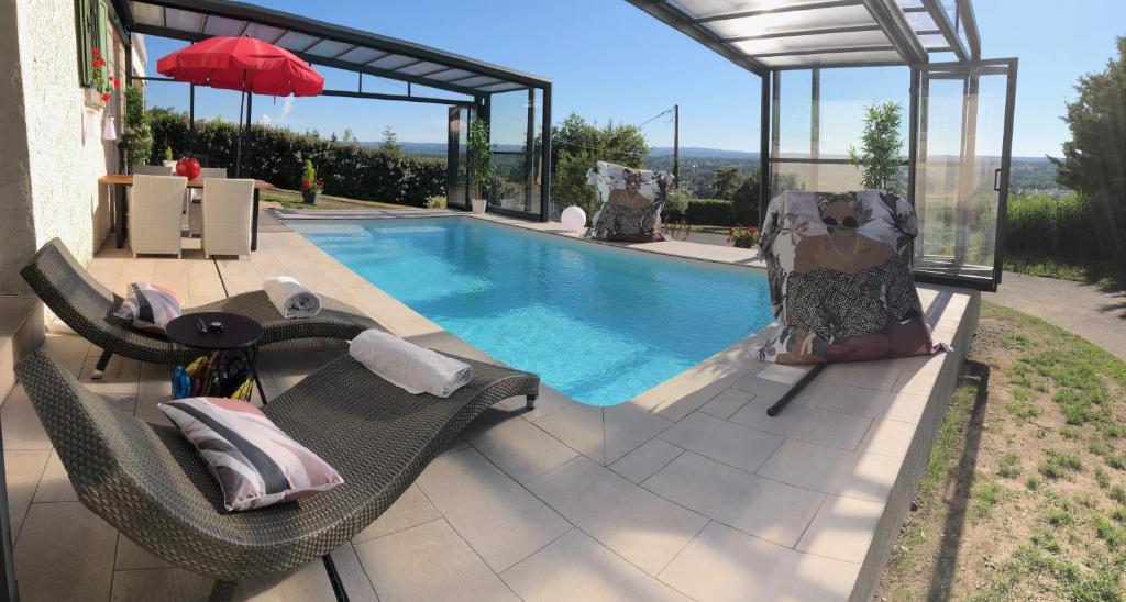 a swimming pool with two chairs and a red umbrella at logement avec piscine couverte chauffée d'avril à octobre et spa privatifs, vue in Estivareilles