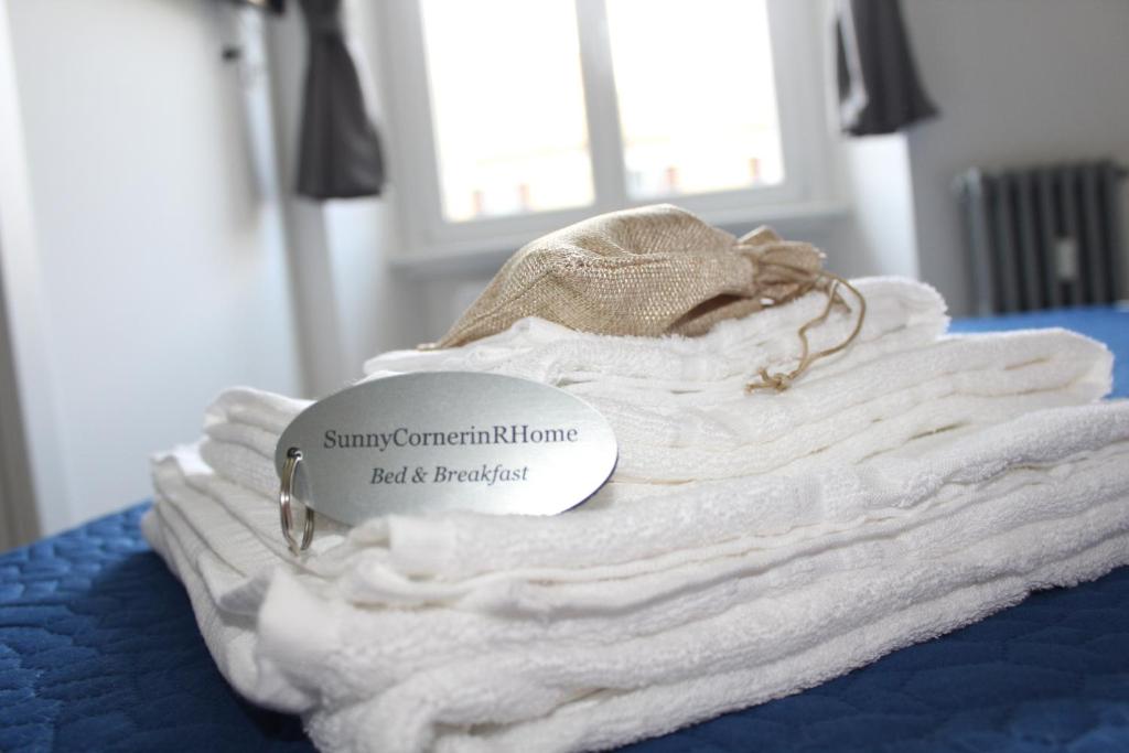 una pila di asciugamani bianchi su un letto con una targhetta di SunnyCornerinRHome a Roma