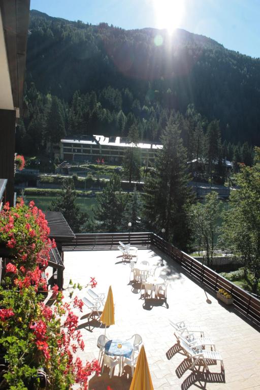 a patio with tables and chairs and a building at Hotel Cristallo in Madonna di Campiglio