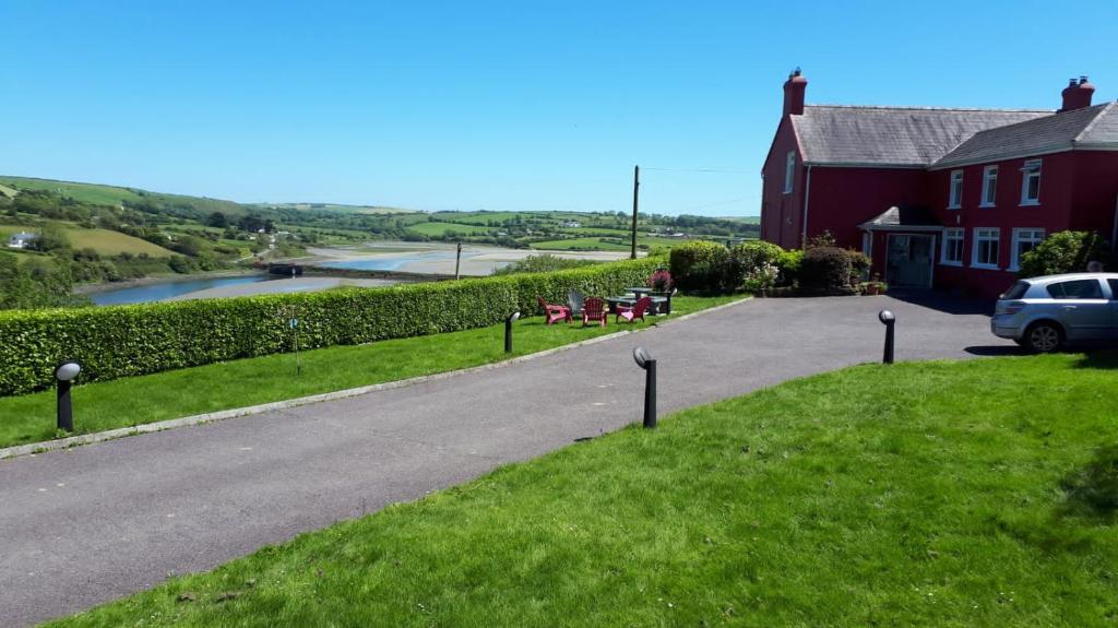 uma estrada ao lado de uma casa e um rio em Bridgeview Farmhouse Bed and Breakfast em Kilbrittain