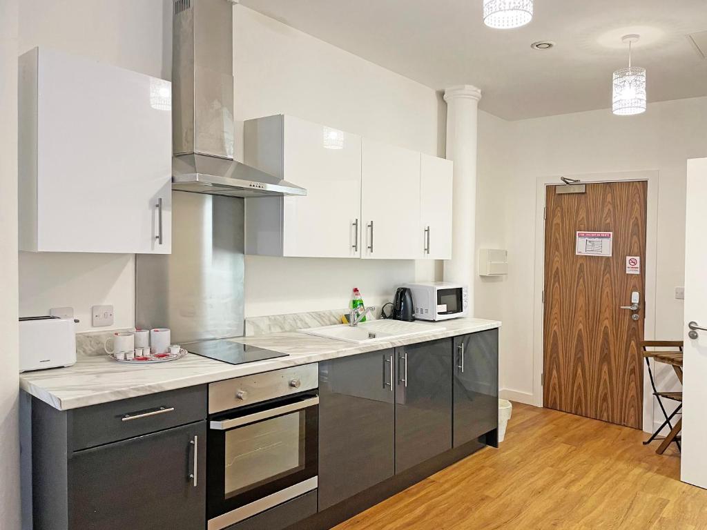 a kitchen with a stove top oven and a microwave at Granite House Apartments in Liverpool