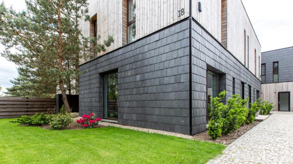 ein schwarzes Haus mit grünem Rasen davor in der Unterkunft Don Vyto in Druskininkai