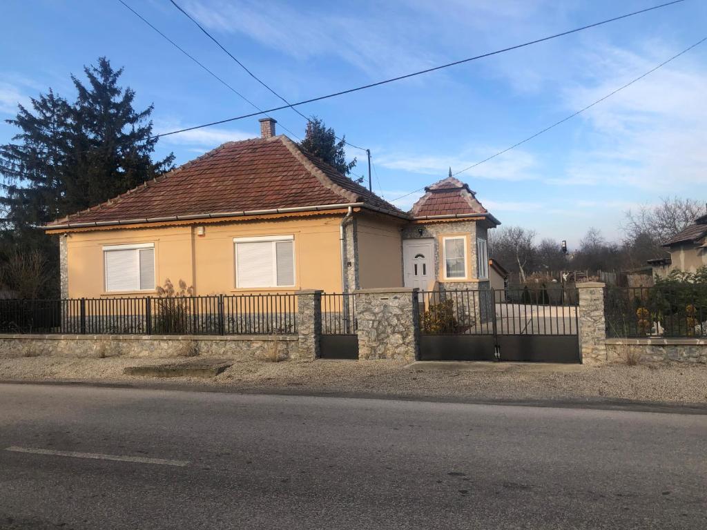 a yellow house with a fence in front of a street at Törpi Apartman in Halmaj