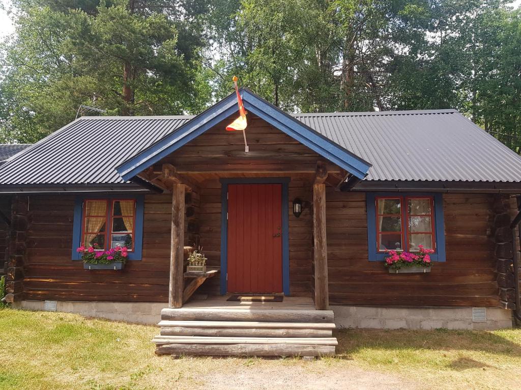 Cabaña de madera con puerta roja y ventanas en Nås Camping Dalarna, stuga nr 6, en Nås