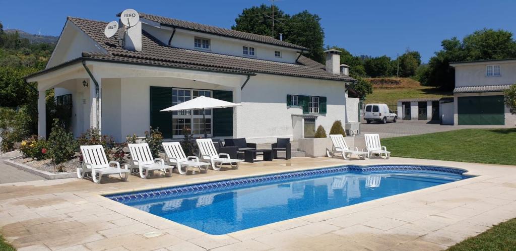 a swimming pool with chairs and a house at Quinta do Paulo in Caramulo
