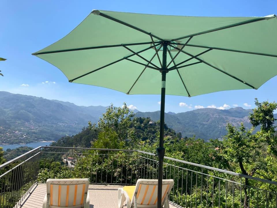 a green umbrella sitting on top of a balcony at Casa de Casarelhos - Andar da Moradia com terraço - Vistas rio - "Gerês" in Geres