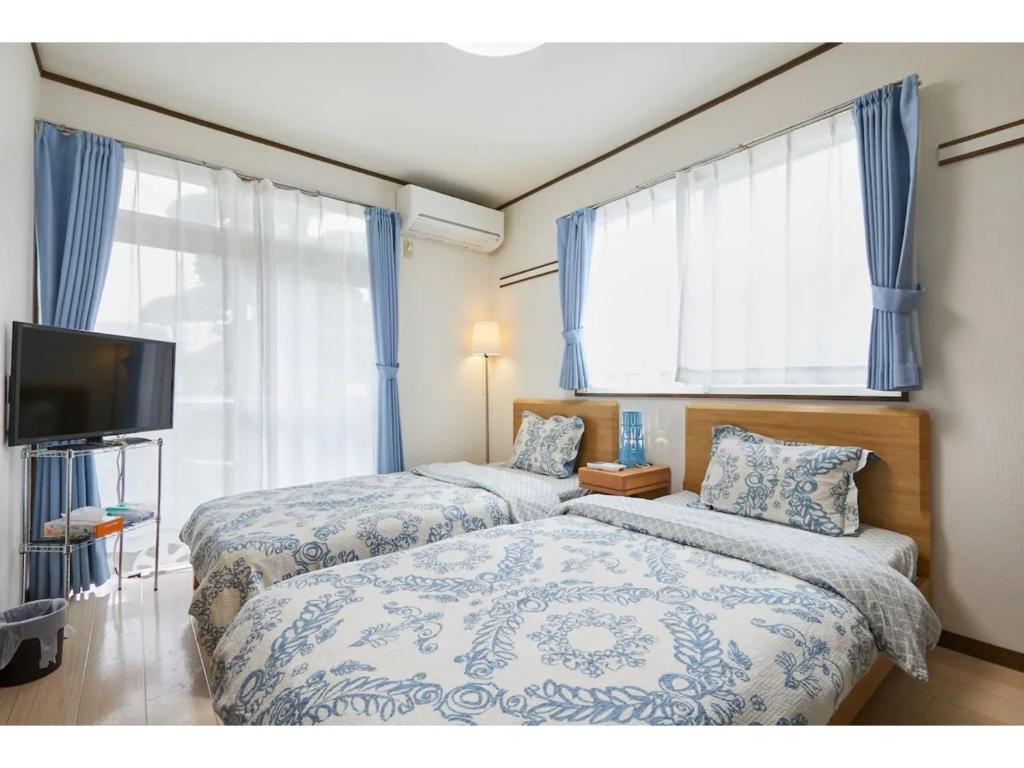 two beds in a bedroom with blue curtains and a tv at La Mer Urayasu - Vacation STAY 11148 in Urayasu
