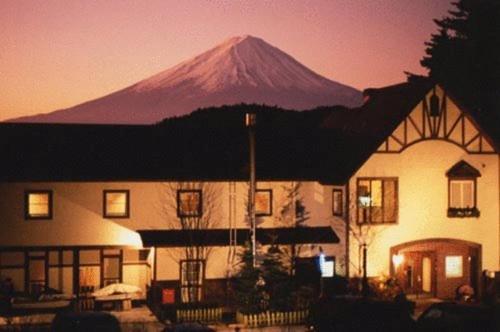 a mountain in the background of a house with a building at Guesthouse Sakuya in Fujikawaguchiko