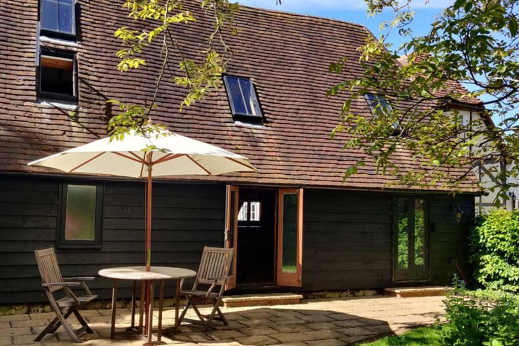 a table with an umbrella in front of a house at Cosy listed barn in peaceful country village in Grandborough