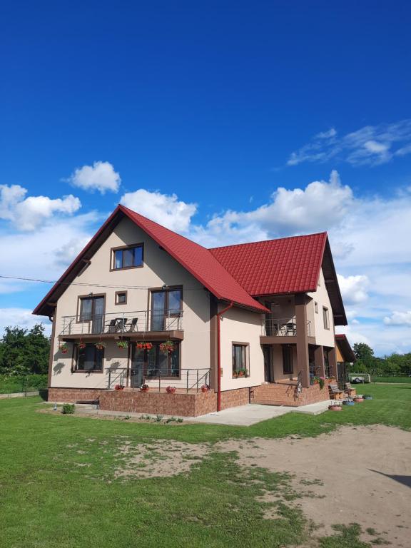 uma casa grande com telhado vermelho em Pensiunea Ana-Maria em Polovragi
