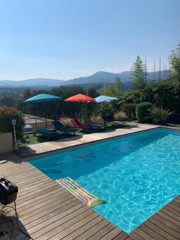 a swimming pool with chairs and umbrellas on a deck at Chambre d'hôtes Le Clos 67 in Saint-Paul-de-Vence