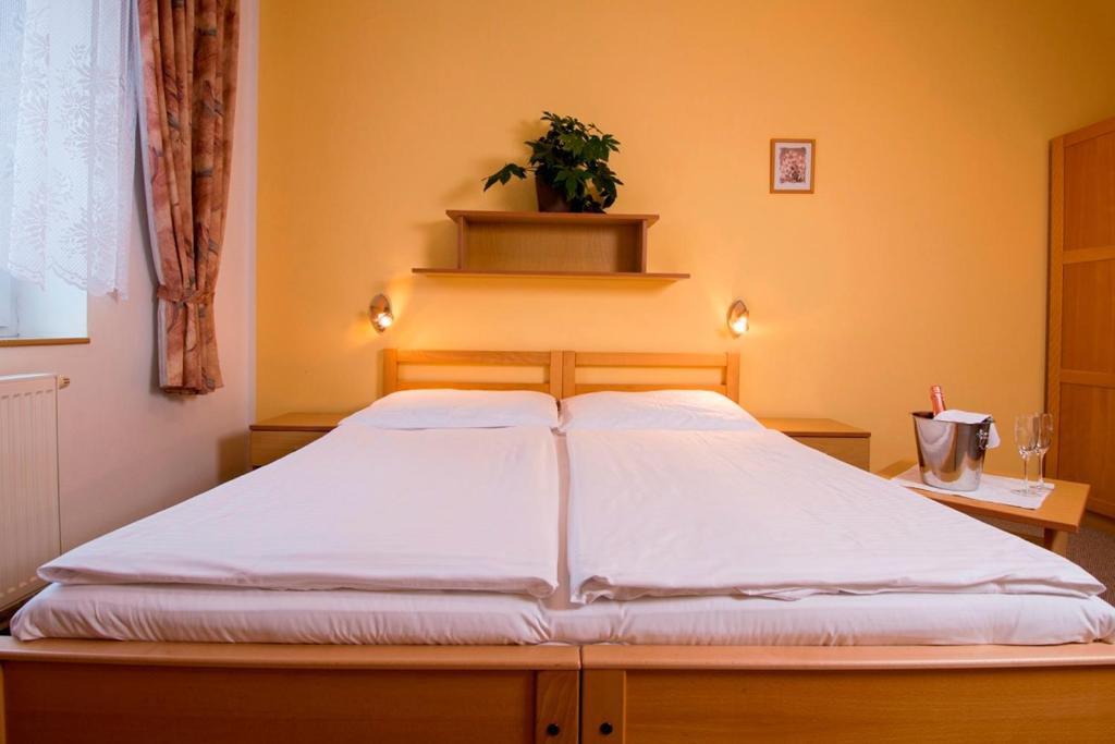een groot bed in een slaapkamer met een plant op een plank bij Penzion Bohemia in Lomnice nad Lužnicí