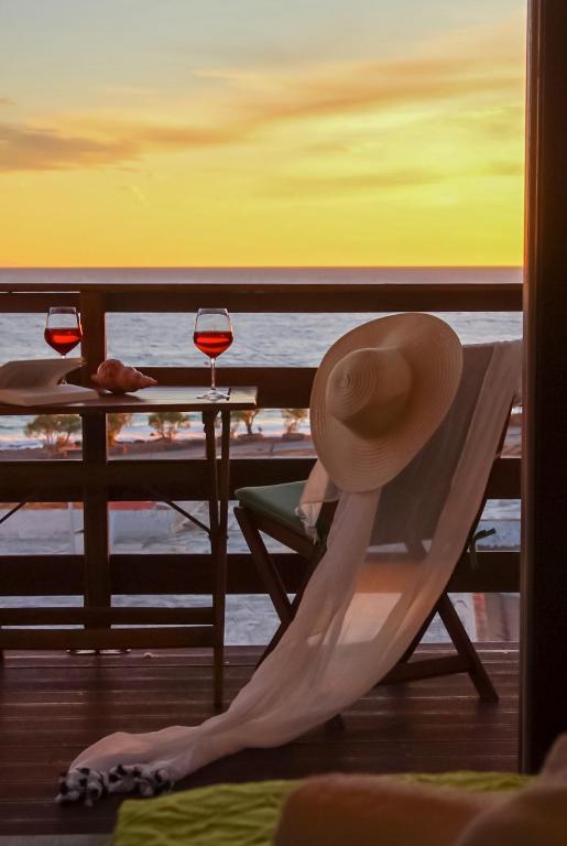 a woman sitting in a chair with a hat and wine glasses at Mistral-Patmos in Patmos