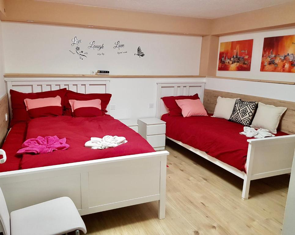 duas camas num quarto com vermelho e branco em Diána Apartman Bogács em Bogács