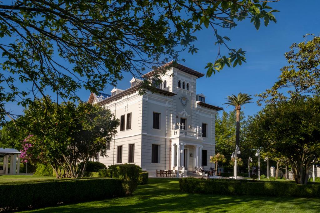 una casa bianca con degli alberi di fronte di Hotel Pazo Libunca a Narón