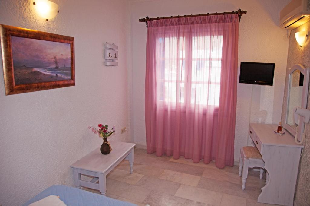 a living room with a pink curtain and a table at St.George Valsamitis in Katapola