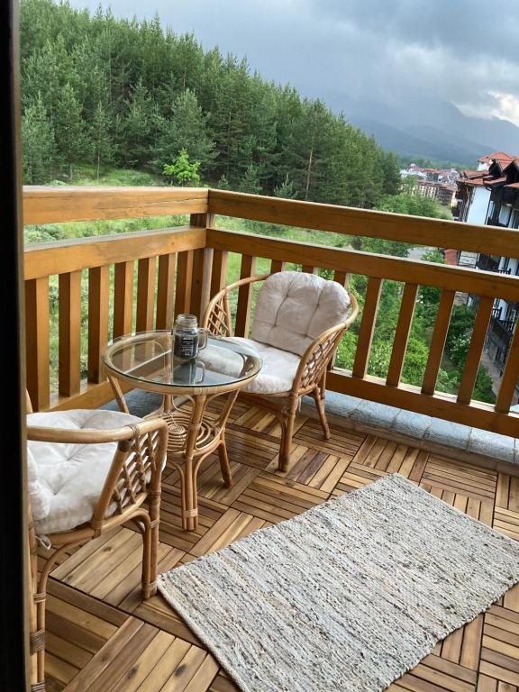a patio with a glass table and chairs on a deck at Mirabell Apartment Bansko - Mountain View & Fireplace in Bansko