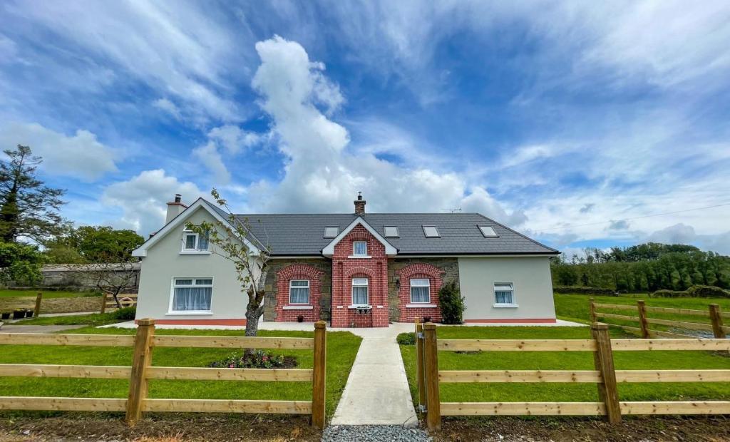 Maison rouge et blanche avec clôture en bois dans l'établissement Drumlanaught Cottage Farnham, à Cavan
