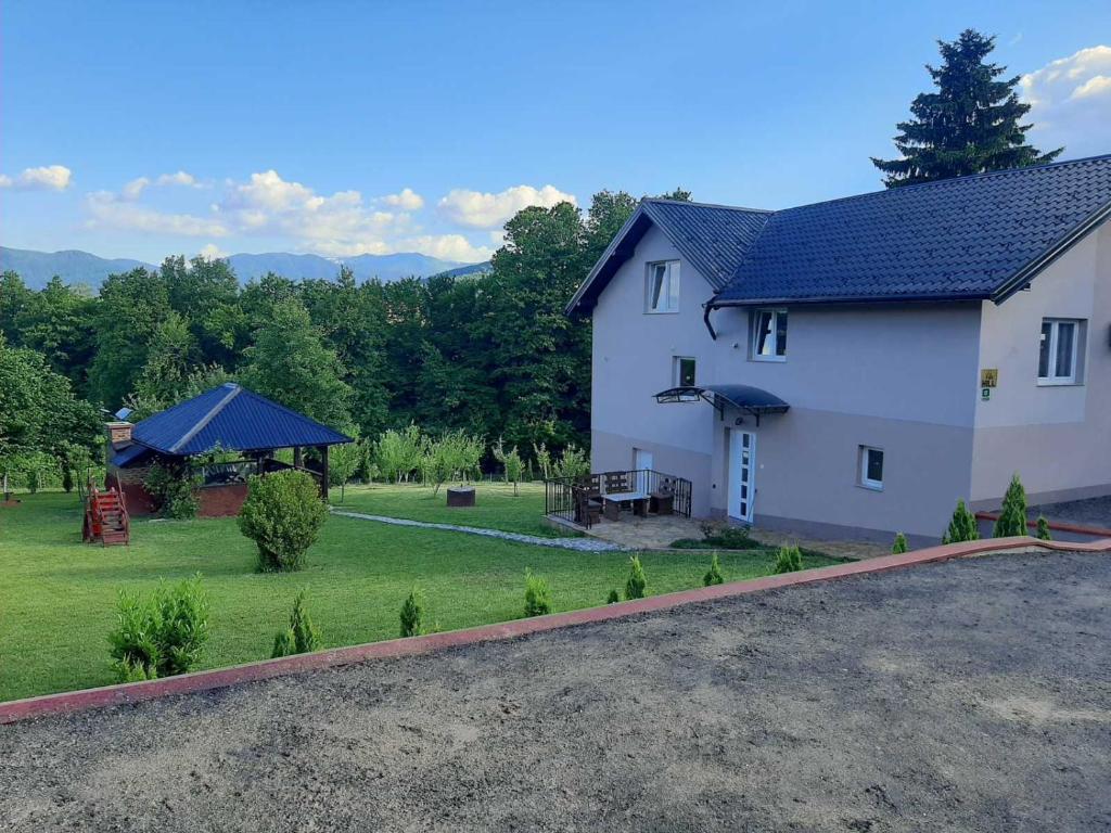a white house with a blue roof and a yard at Hil in Rakovica