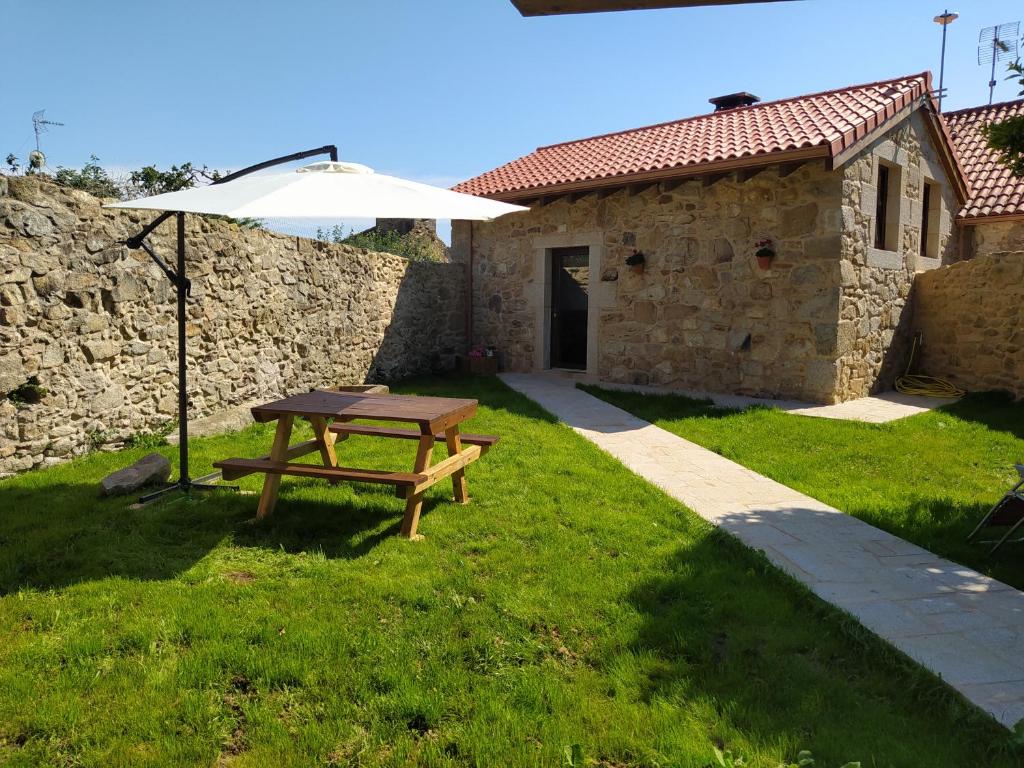 un tavolo da picnic di fronte a un edificio in pietra con ombrellone di O RINCÓN DE NOAH a Finisterre