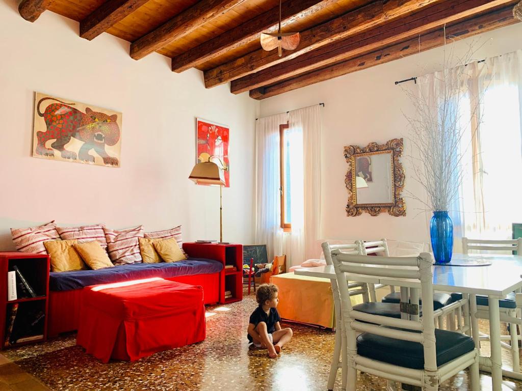 Un niño pequeño sentado en el suelo en una sala de estar en La Casa Del Pittore, en Venecia