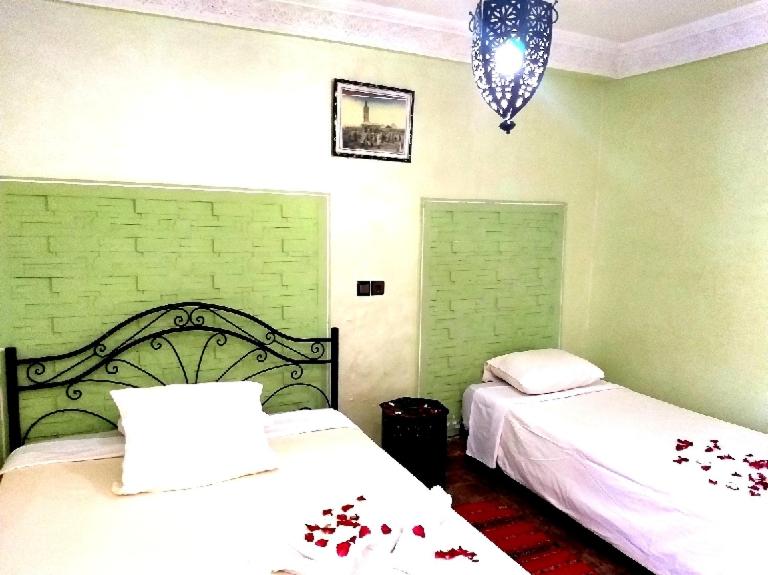 Hôtel Agnaou في مراكش: غرفة نوم بسريرين وعليها ورد