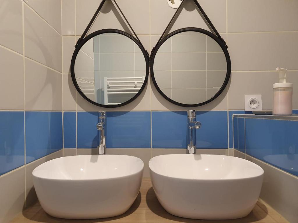 a bathroom with two sinks and two mirrors at Le triangle d or in Bordeaux