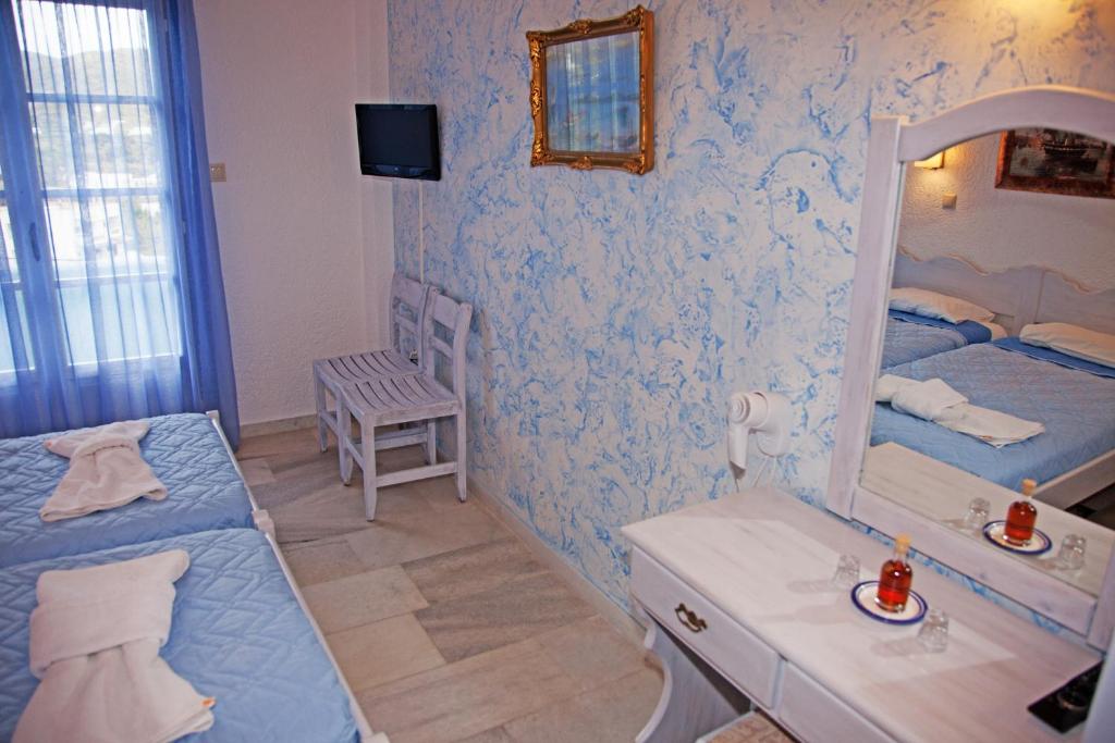 a blue and white bedroom with a bed and a mirror at St.George Valsamitis in Katapola